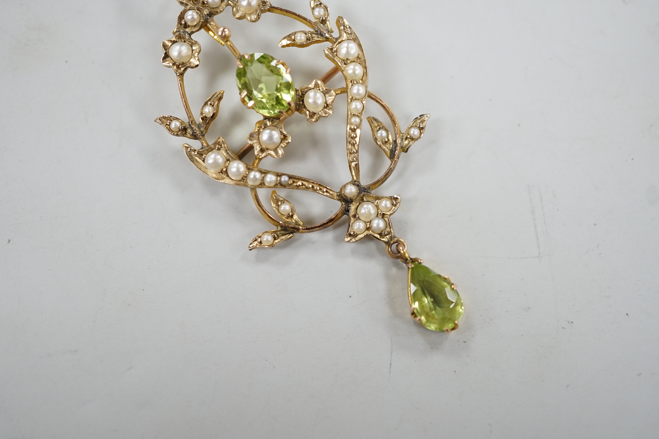 An Edwardian 9ct, peridot and seed pearl set drop pendant brooch, 57mm, on a later 375 rope twist chain, 44cm gross weight 6.7 grams.